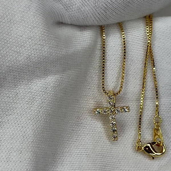 The perfect tiny cross pendant for stacking with other necklaces!  18k gold plated, A+++ crystal, round cut stone cross pendant necklace. Pendant is approximately 1/2" in length and attached to a dainty 18k gold box chain necklace. Pendant can be removed  and placed on any other chain.   Stack it with the Say My Name Necklace and Cross to Bear Necklace for a complete look!  Expect to get up to 1 year worth of tarnish proof, water resistant wear from our jewelry with proper care. Hypoallergenic.