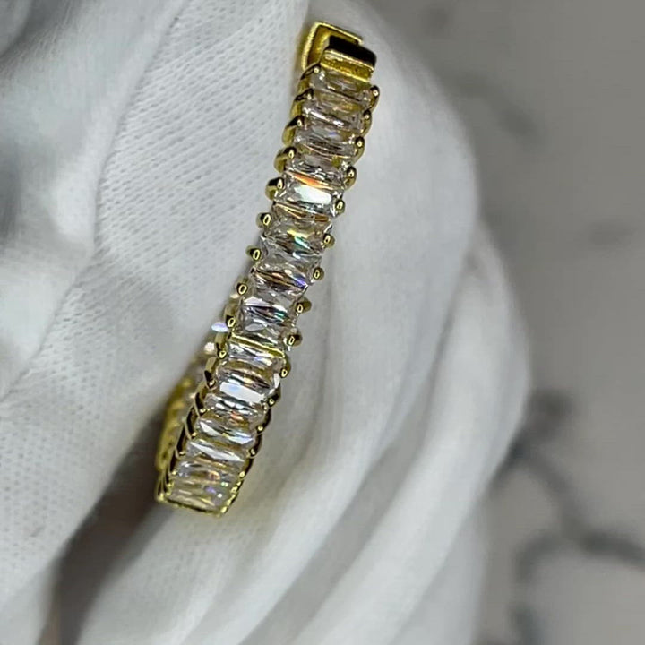 There's nothing like a good baguette, diamond hoop and the Baguette Me Earrings are just that and a must add to any collection!   1" circumference, 18k gold plating with baguette A+++ CZ stones surrounding the entire earring.  Expect to get up to 1 year worth of tarnish proof, water resistant wear from our jewelry with proper care. Hypoallergenic.