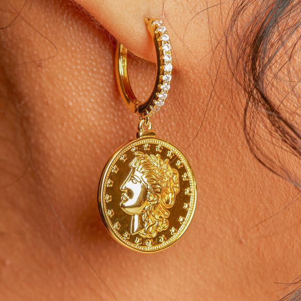 Who can really resist these unique and head turning stunners? The My Coin Earrings make a statement all on their own!   18k gold plated, A+++ crystal, dangle, coin drop earrings.   Paired perfectly here with the Tiny Cross Necklace and the Micro Bling Ring.  Expect to get up to 1 year worth of tarnish proof, water resistant wear from our jewelry with proper care. Hypoallergenic.